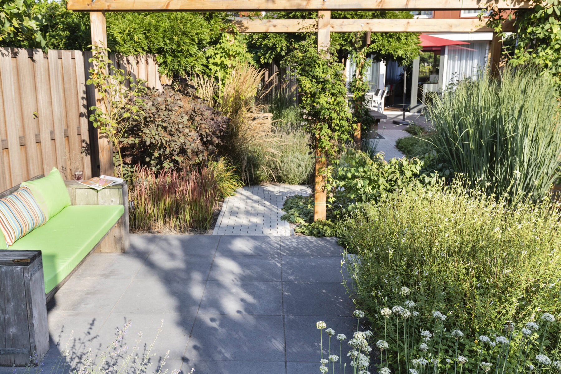 Kleine ommuurde stadstuin met privacy, gelaagde beplanting en een terras