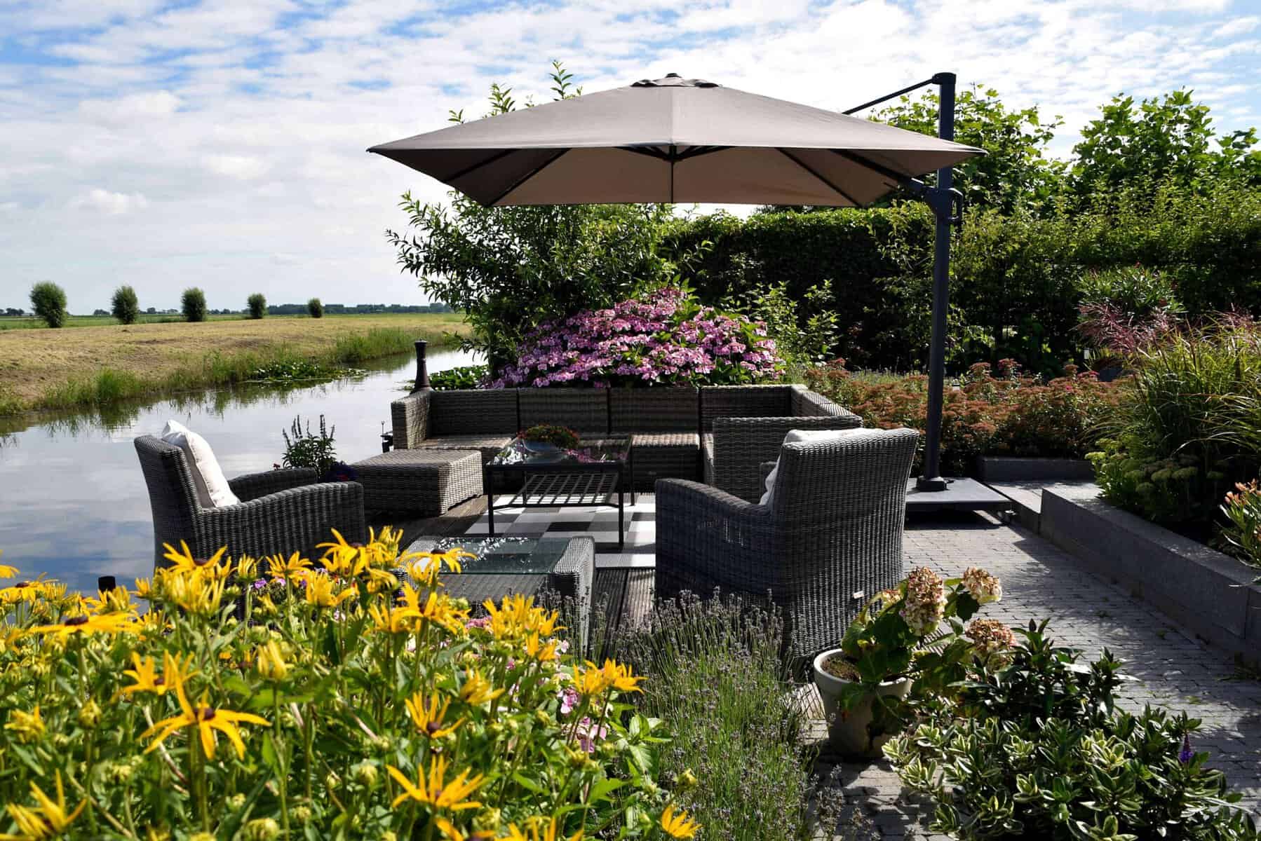 Gezellige tuin aan het water met zithoek en parasol.