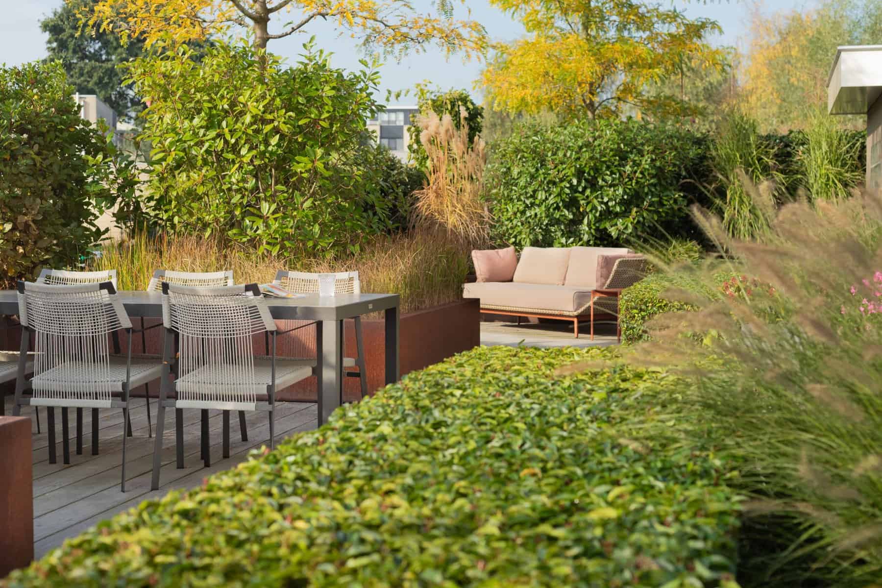 Gezellige tuin met zithoek, groene planten en kleurrijke bloemen.