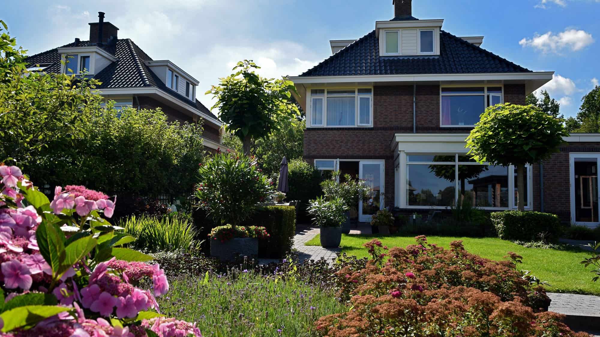 Moderne woning met groene tuin en kleurrijke bloemen.