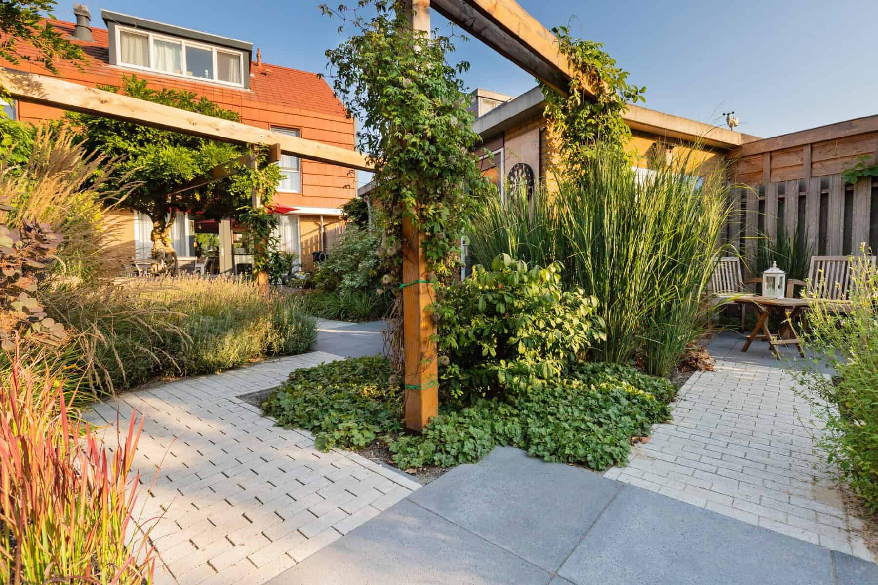 Gezellige tuin met terras, groene planten en houten pergola.