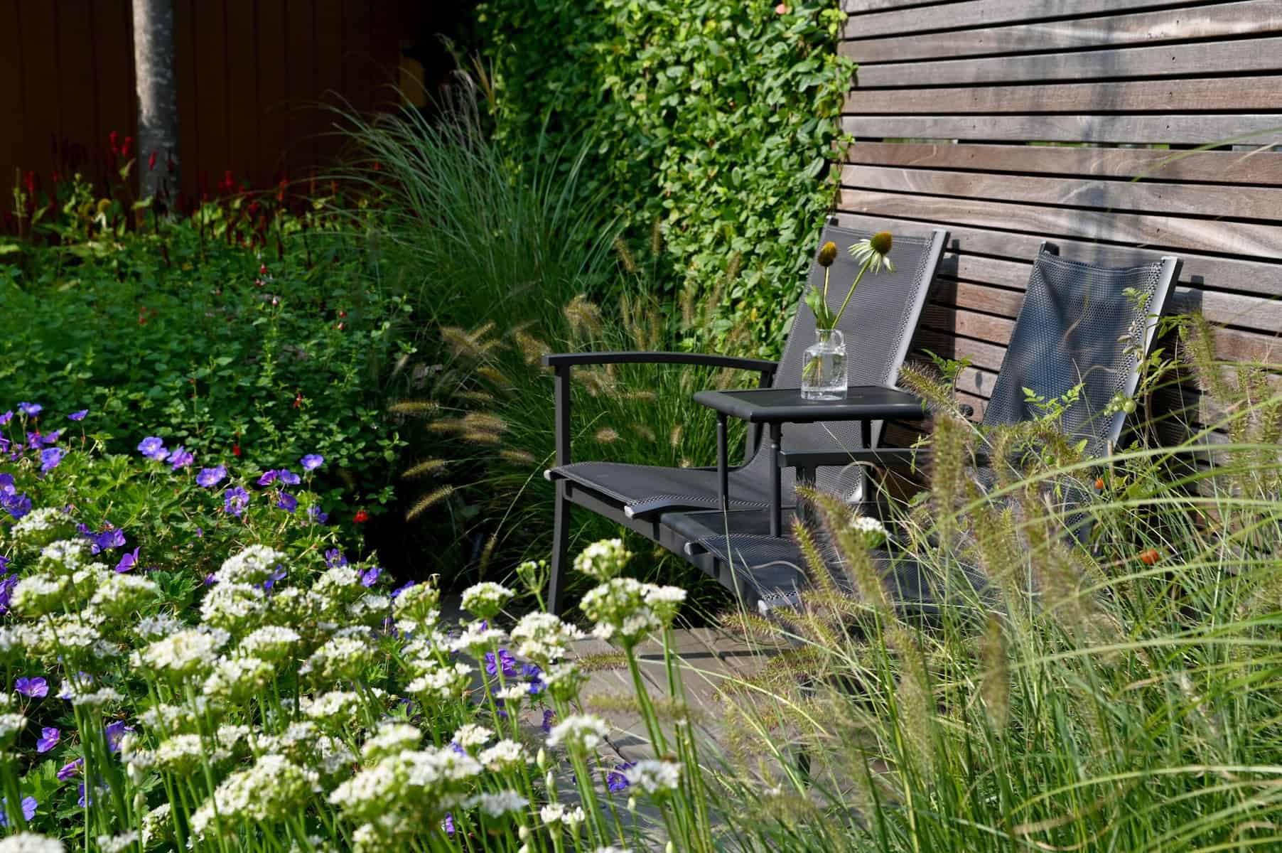 Tuinset met twee stoelen en tafel in een groene tuin.