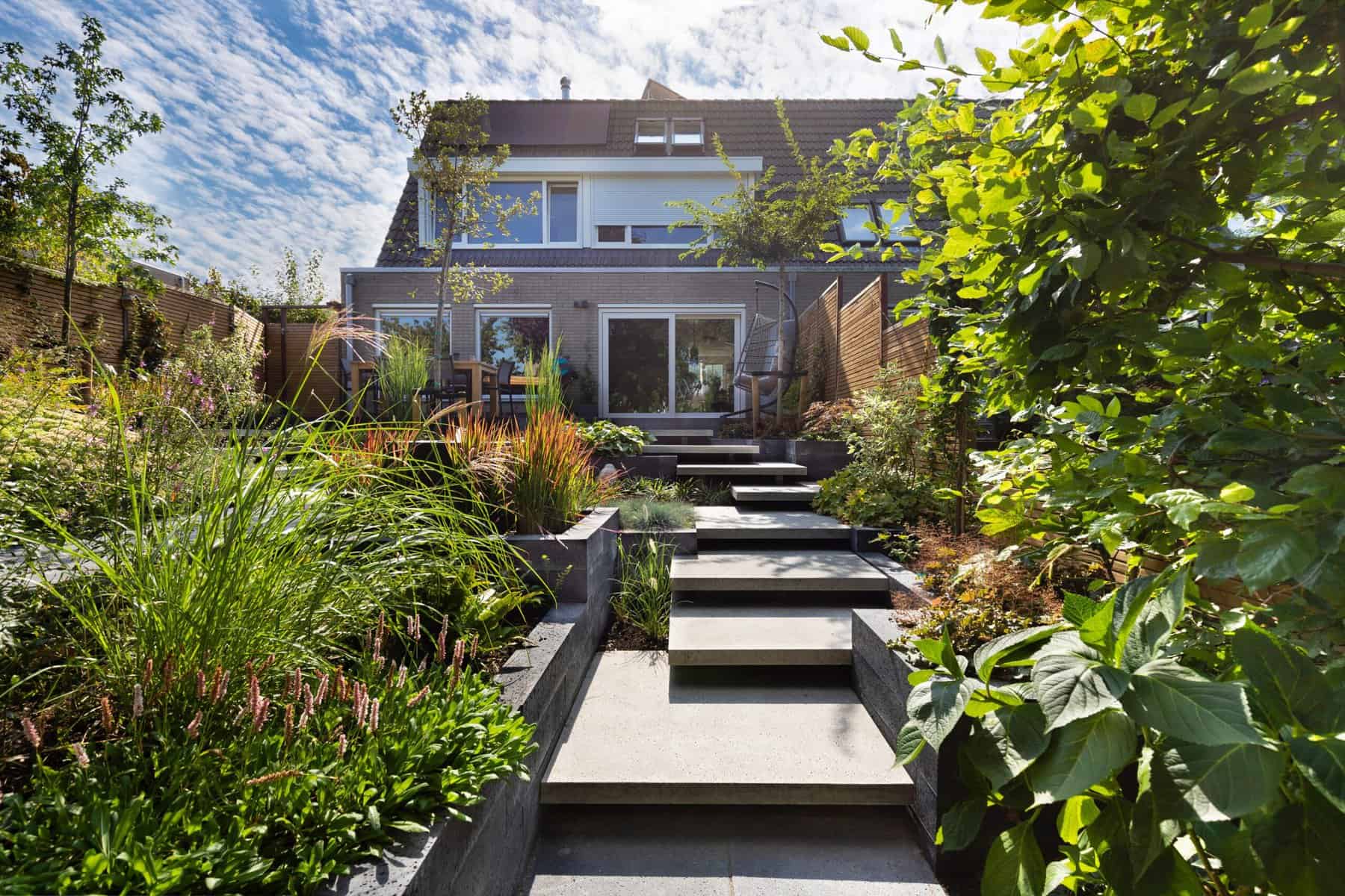Moderne tuin met terras, planten en tuinpad voor een groene buitenruimte.