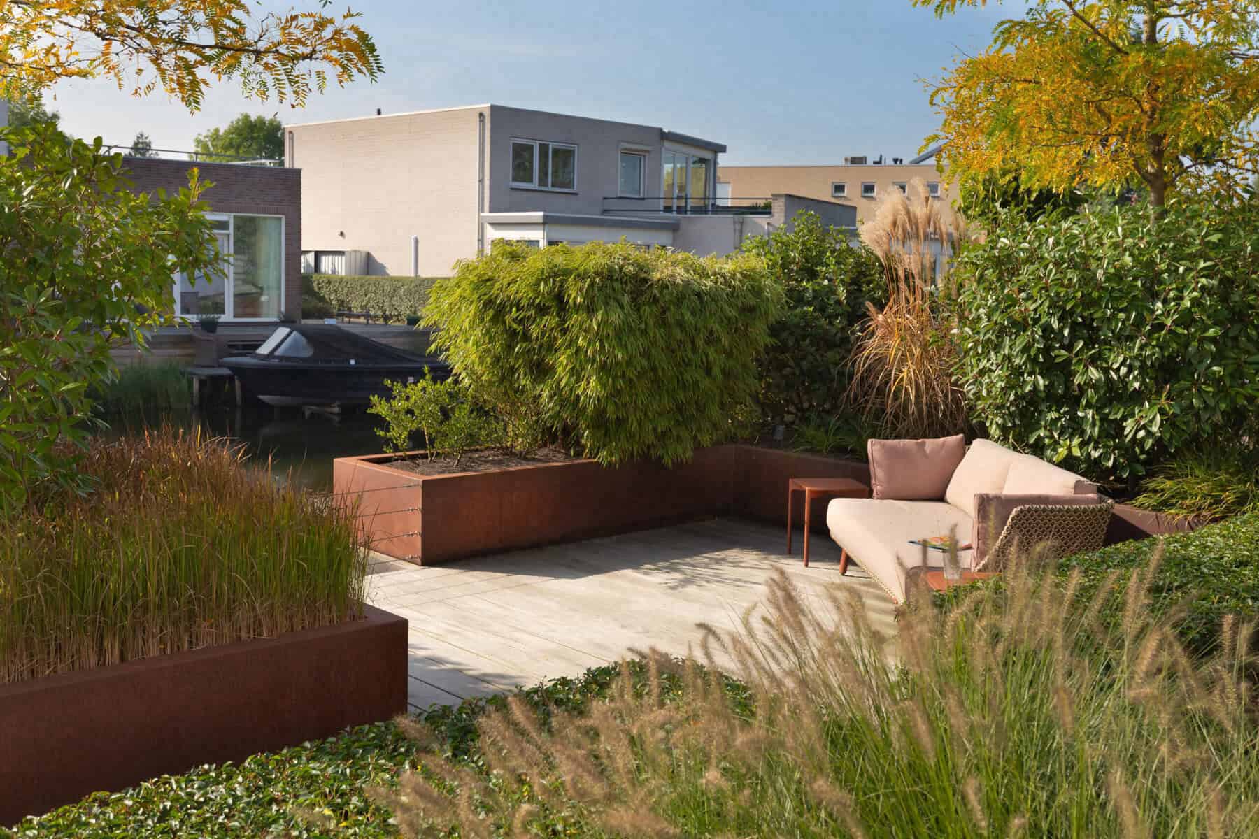 Loungehoek in een tuin aan het water met moderne tuinmeubels.