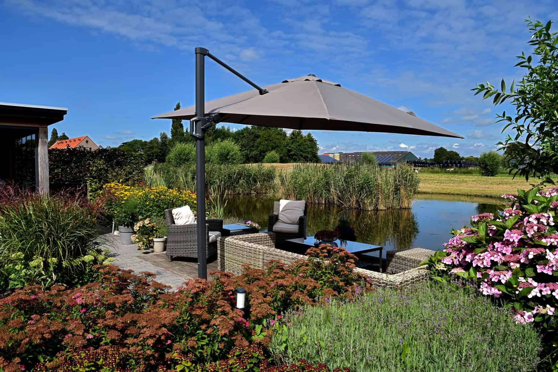 Tuin met terras, parasol en uitzicht op water en natuur.