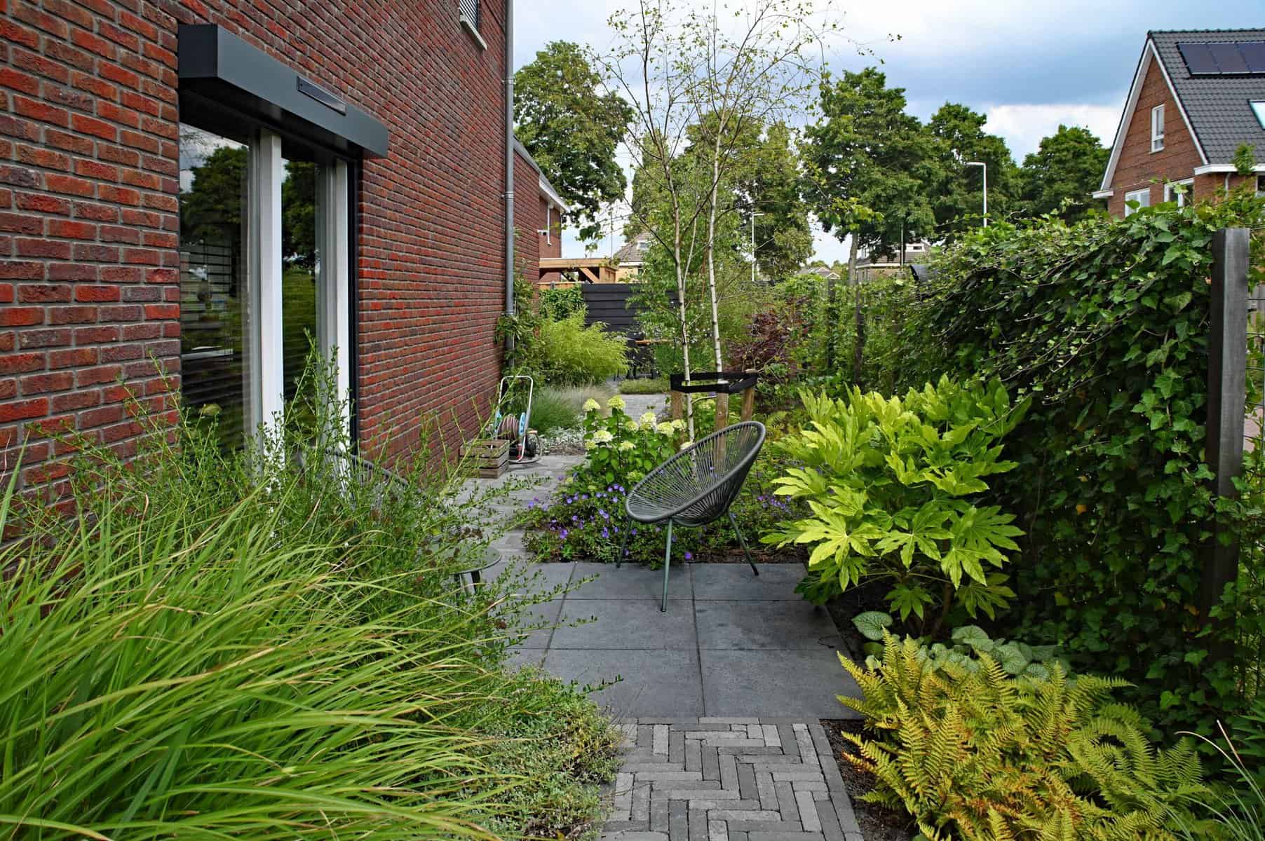Gezellige tuin met zitplek, groen en bloemen voor een natuurlijke uitstraling.