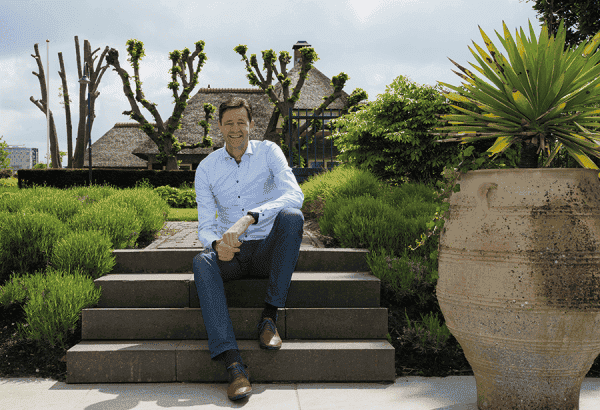 Tuinman in een natuurlijke tuin met grote planten en bomen.