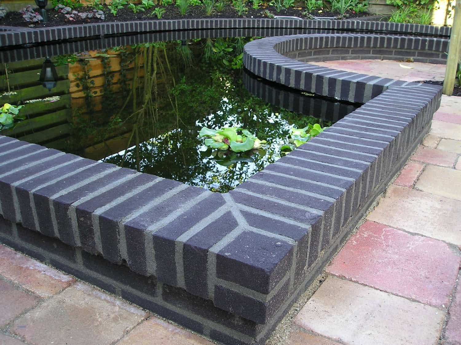 Tuin met vijver en zwarte rand, rustiek tuinontwerp.